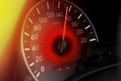 Speedometer on car dashboard under yellow light, closeup