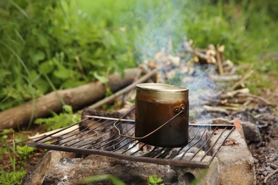 Photo of Cooking food on rack over bonfire in wilderness
