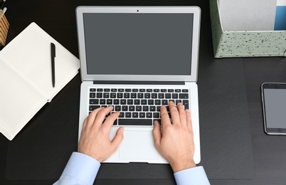 Young man using modern laptop at table, top view