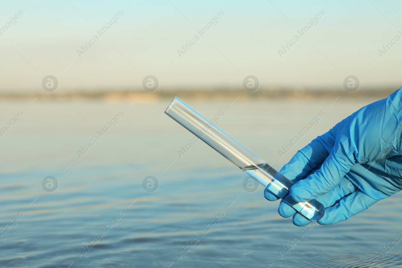 Photo of Scientist with test tube taking sample from river for analysis, closeup