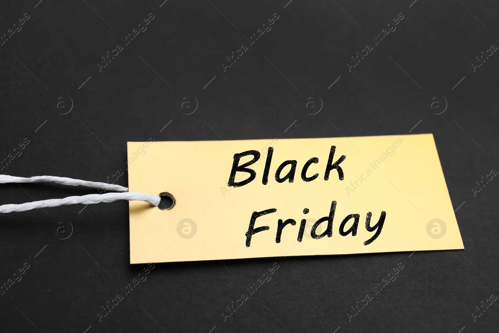 Photo of Golden blank tag on dark background, closeup. Black Friday concept