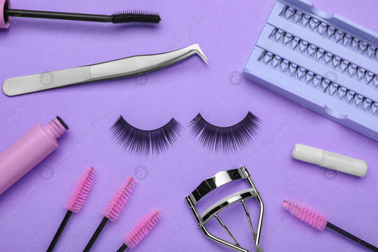 Photo of Flat lay composition with fake eyelashes, brushes and tools on lilac background