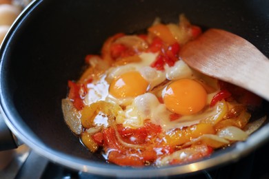 Photo of Cooking tasty eggs with vegetables in frying pan, closeup