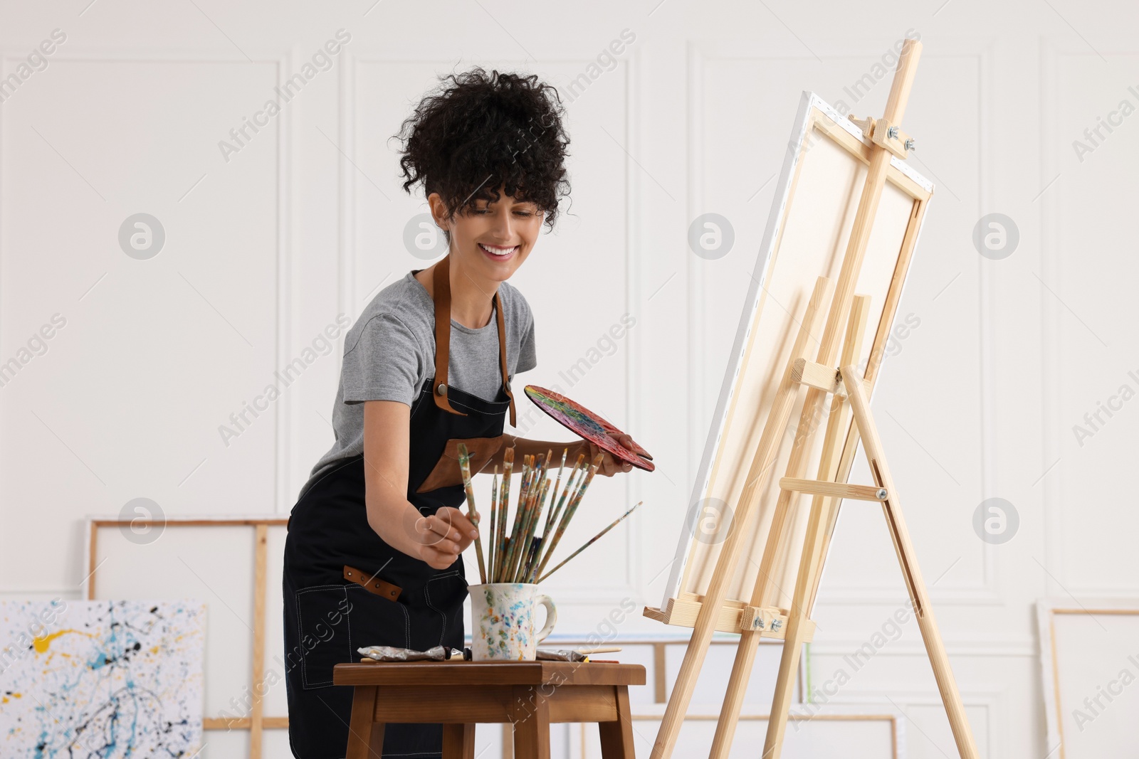 Photo of Young woman taking brush from mug in studio