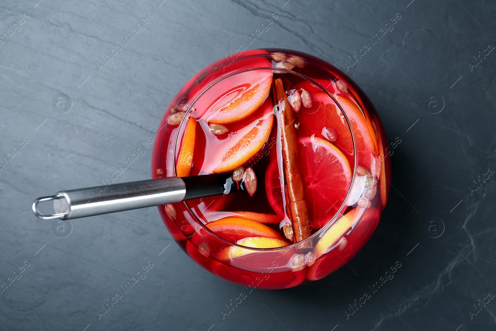 Photo of Glass bowl of aromatic punch drink on black table, top view