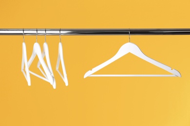 Photo of Metal rack with clothes hangers on color background