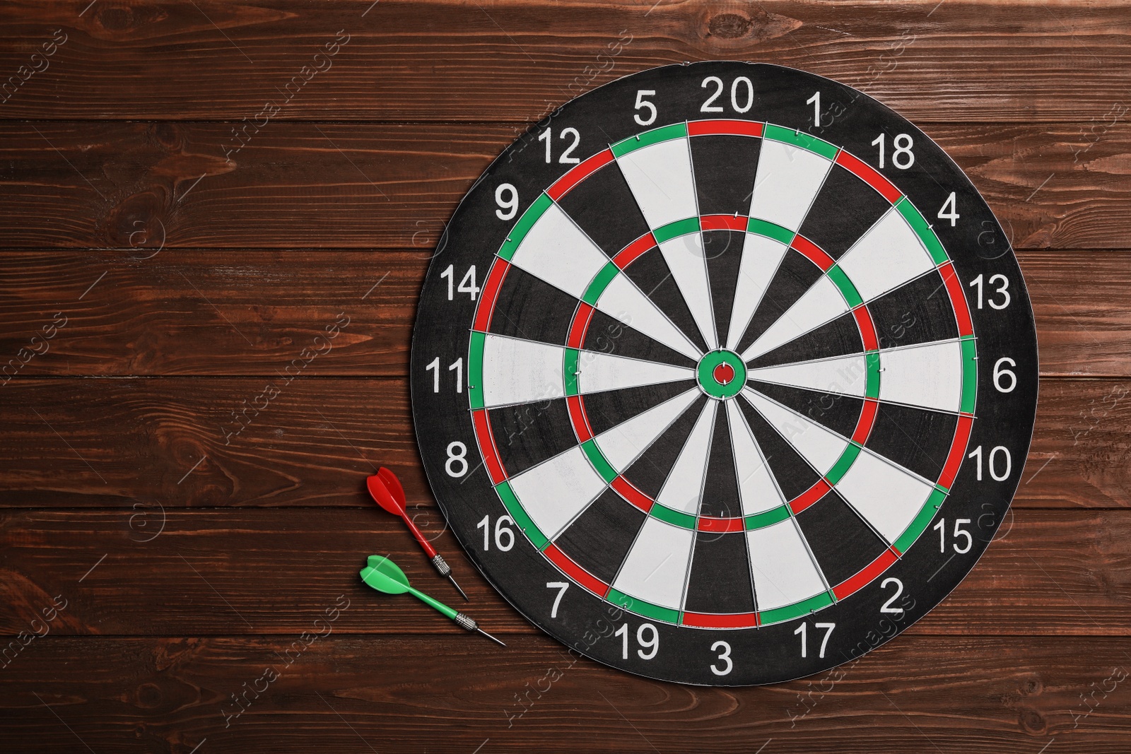 Photo of Dart board with color arrows on wooden background, top view. Space for text