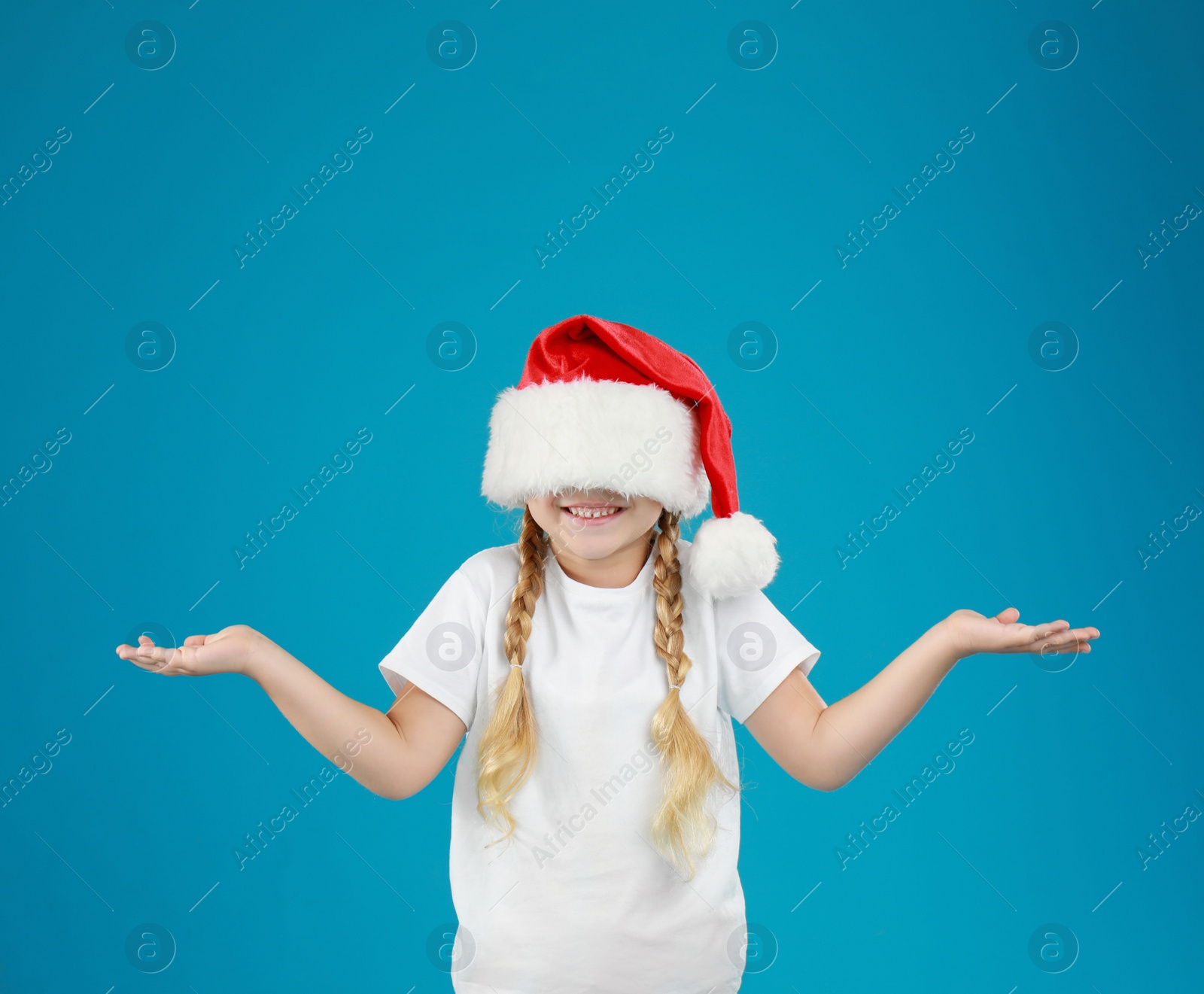 Photo of Cute little child wearing Santa hat on blue background. Christmas holiday