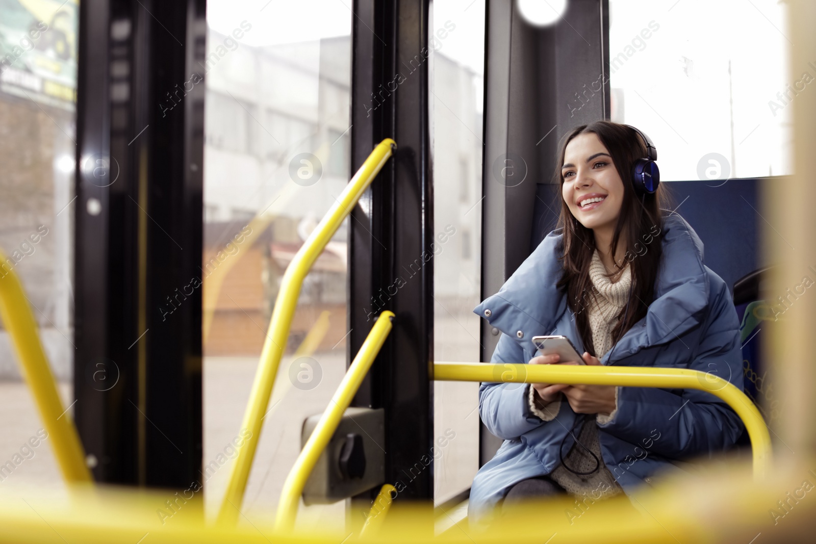 Photo of Young woman listening to music with headphones in public transport