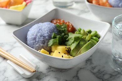 Photo of Poke bowl served on white marble table, closeup