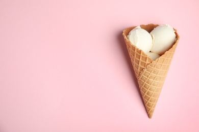 Photo of Delicious vanilla ice cream in wafer cone on pink background, top view. Space for text