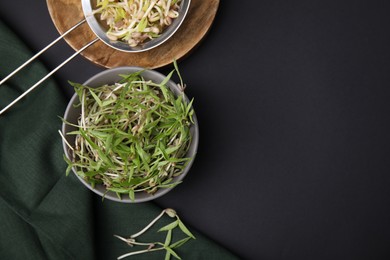 Photo of Mung bean sprouts with bowl and strainer on black table, flat lay. Space for text