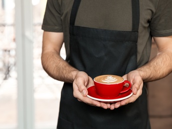 Photo of Barista with cup of coffee in shop, closeup. Space for text