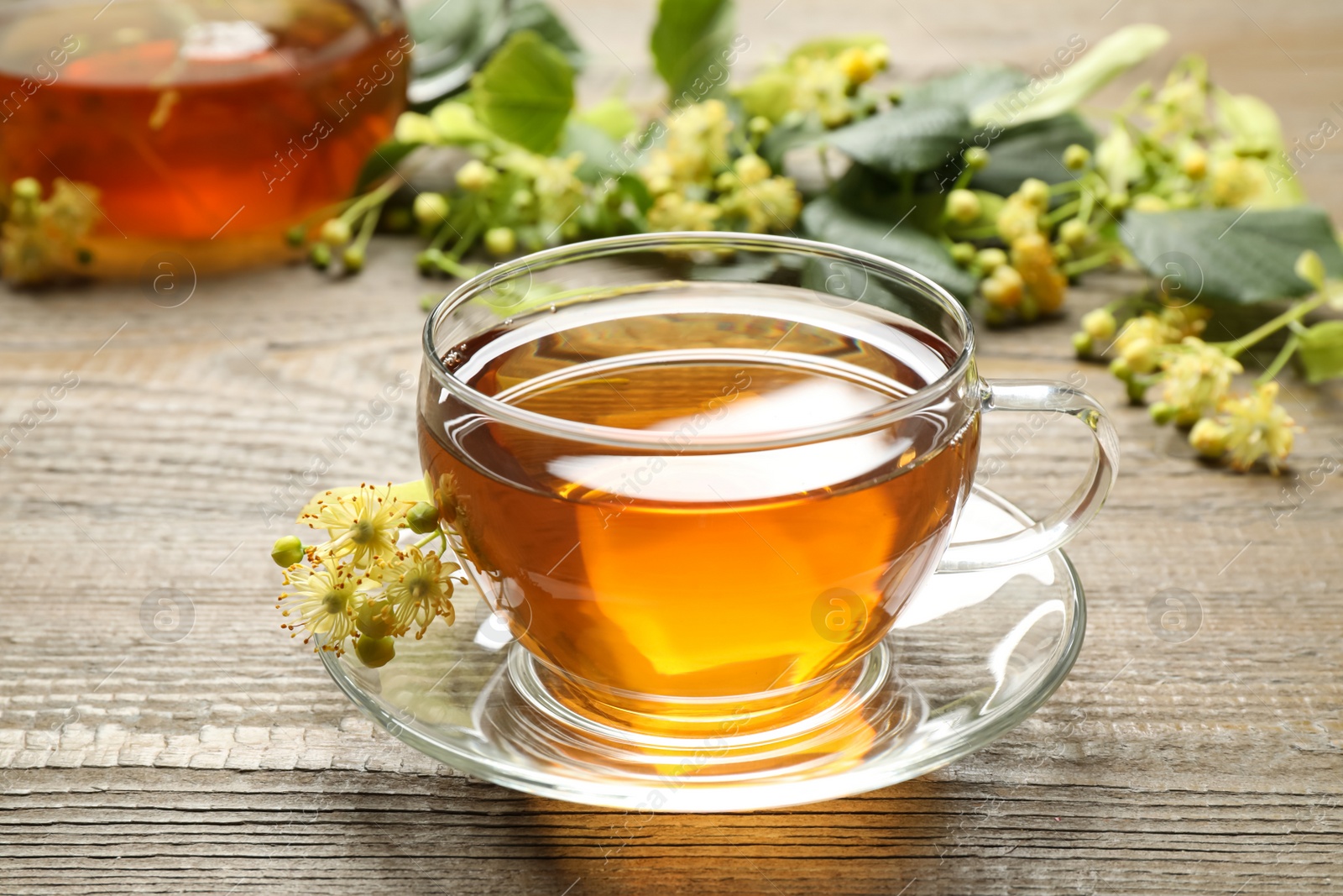 Photo of Cup of tea and linden blossom on wooden table