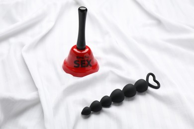 Anal beads and bell with text Ring For Sex on white fabric