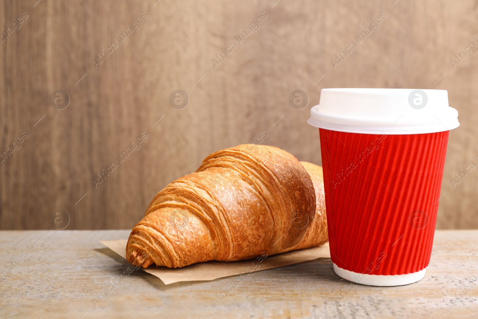 Photo of Tasty fresh croissant and drink on wooden table