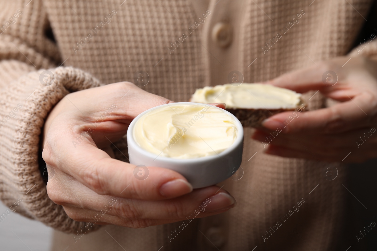 Photo of Woman holding slice of bread and butter, closeup