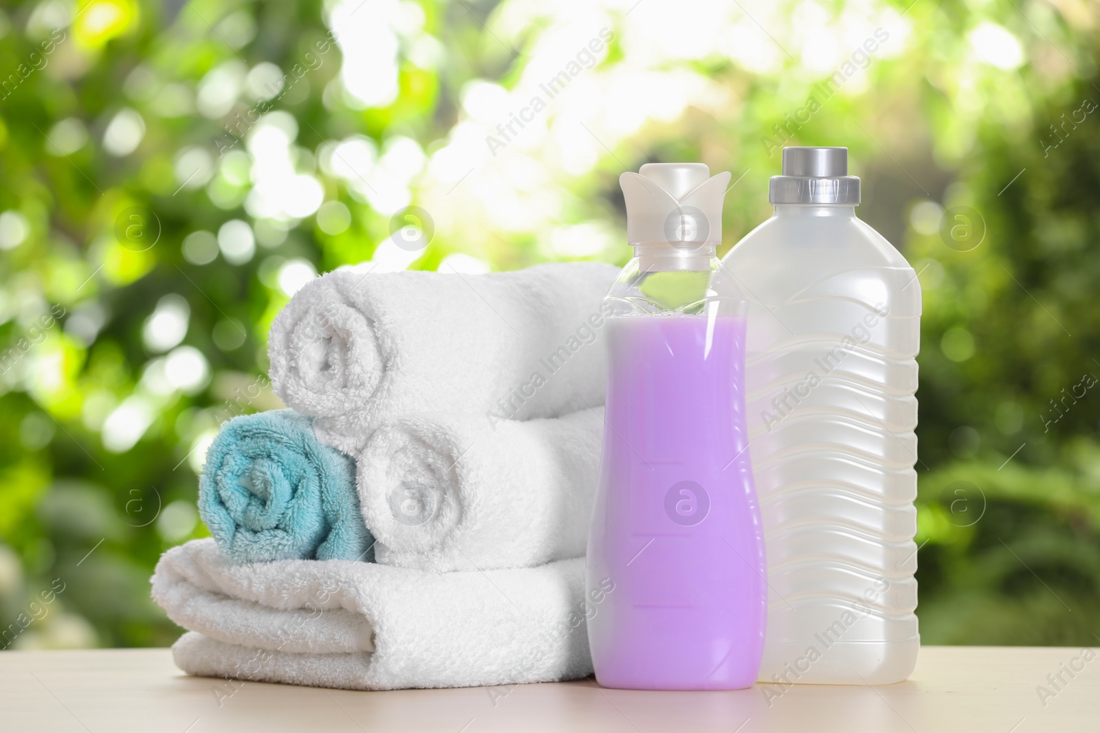 Photo of Soft bath towels and laundry detergents on table against blurred background