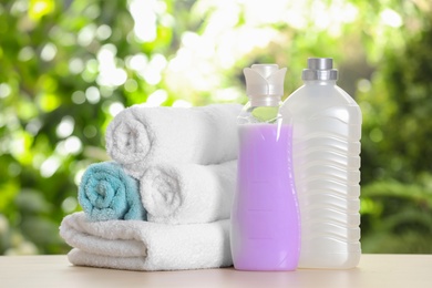 Soft bath towels and laundry detergents on table against blurred background