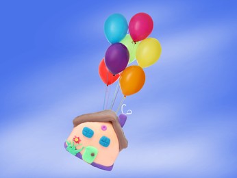 Image of Many balloons tied to playdough house flying on blue background