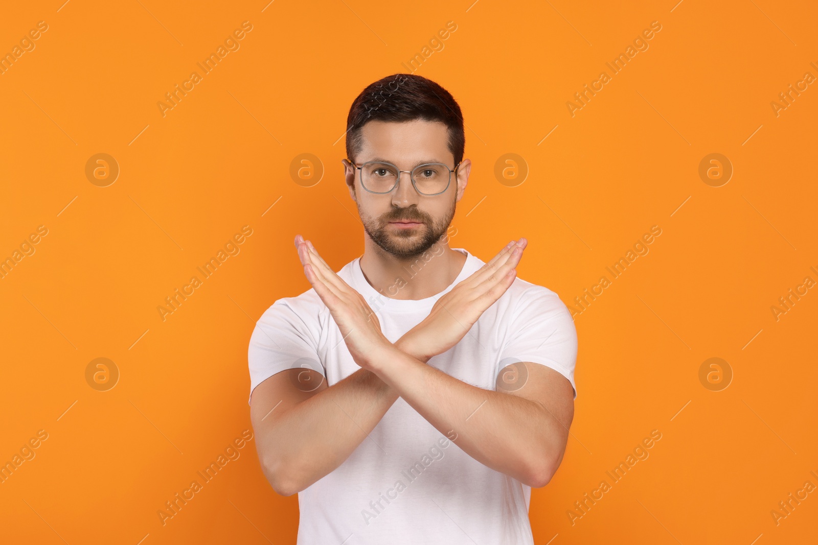 Photo of Handsome man with crossed hands on orange background. Stop gesture