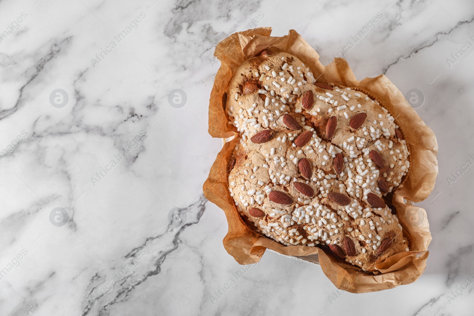 Photo of Delicious Italian Easter dove cake (Colomba di Pasqua) on white marble table, top view. Space for text