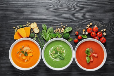 Photo of Flat lay composition with various soups and ingredients on wooden background. Healthy food