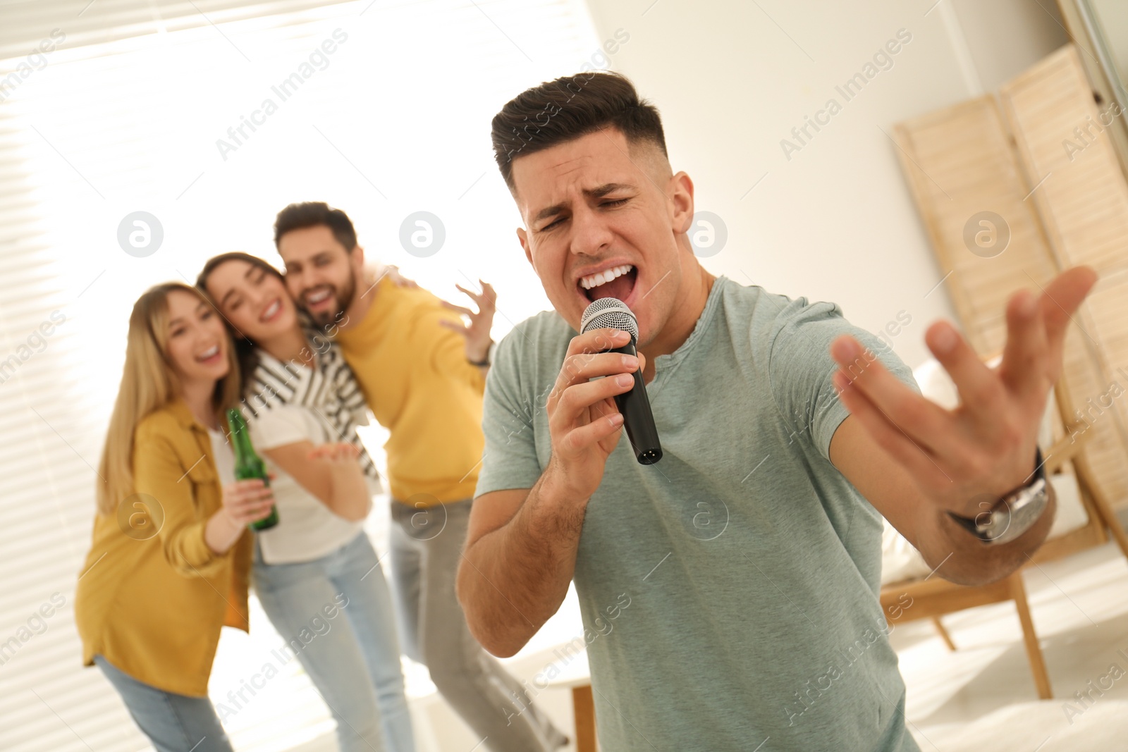 Photo of Man singing karaoke with friends at home