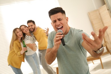 Photo of Man singing karaoke with friends at home