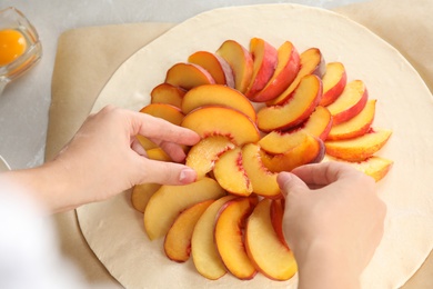 Photo of Woman making peach pie at table, closeup