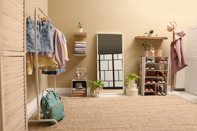 Stylish dressing room interior with trendy clothes and shoes