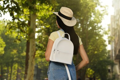 Photo of Young woman with stylish white backpack on city street, back view