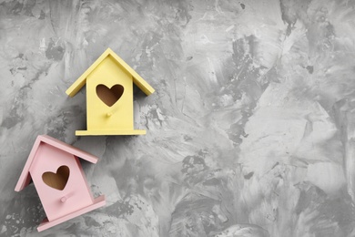 Photo of Beautiful bird houses with heart shaped holes on light grey background, flat lay. Space for text