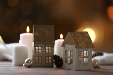 Photo of Composition with house shaped candle holder on wooden table against blurred lights, space for text. Christmas decoration