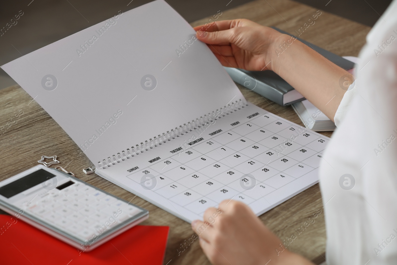 Photo of Woman with calendar at wooden table, closeup