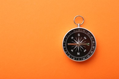 Photo of One compass on orange background, top view. Space for text