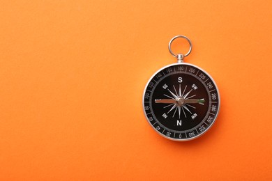 One compass on orange background, top view. Space for text