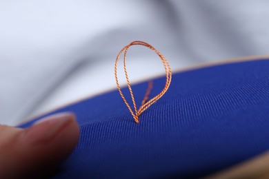 Photo of Woman with sewing thread embroidering on cloth, closeup