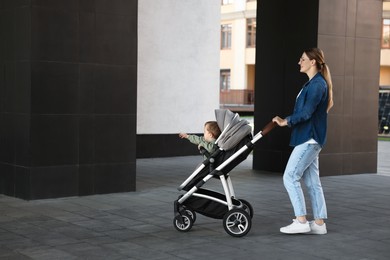 Beautiful nanny with cute little boy in stroller walking outdoors