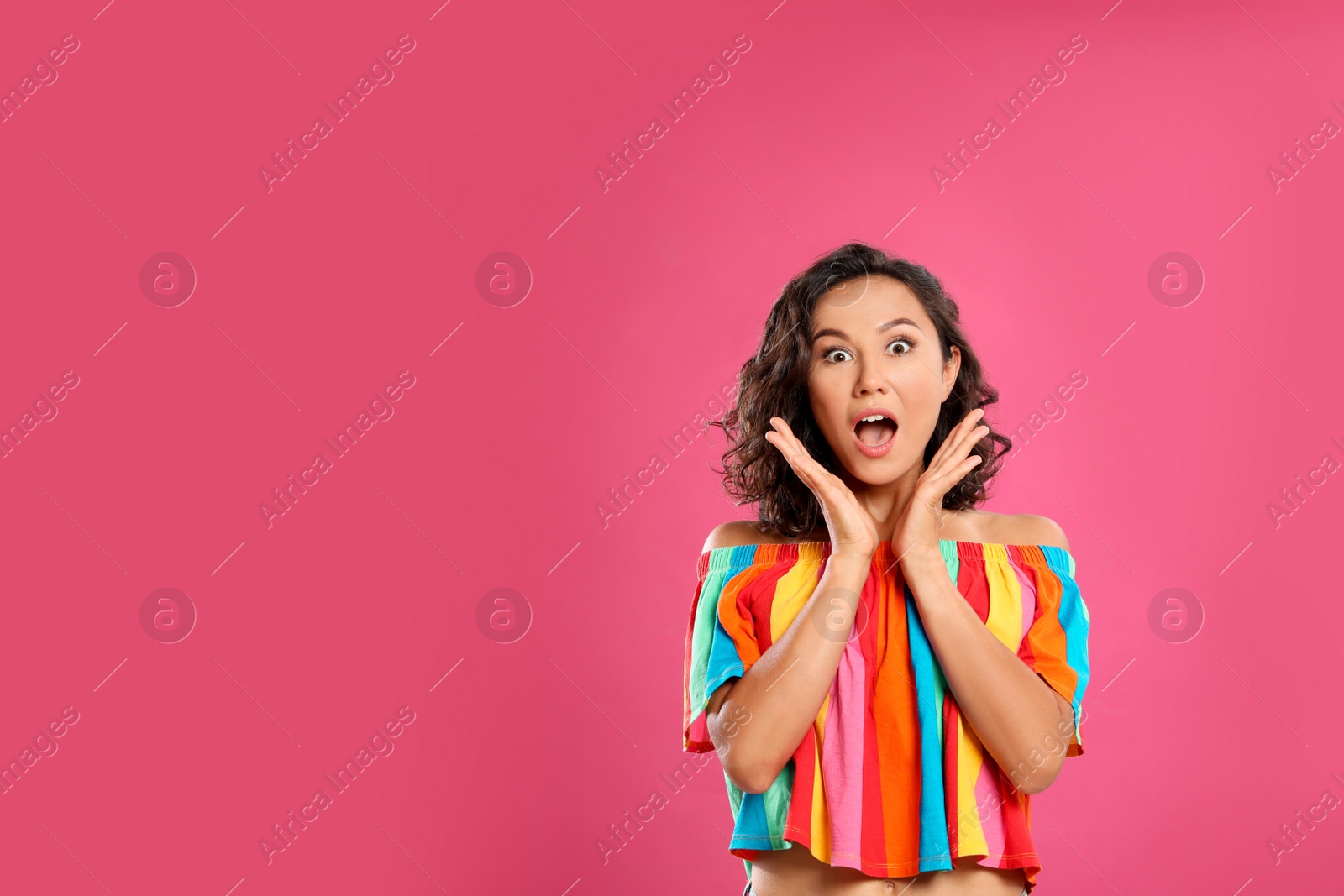 Photo of Surprised young woman in casual outfit on pink background. Space for text