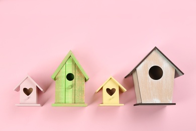 Photo of Collection of handmade bird houses on pink background, flat lay