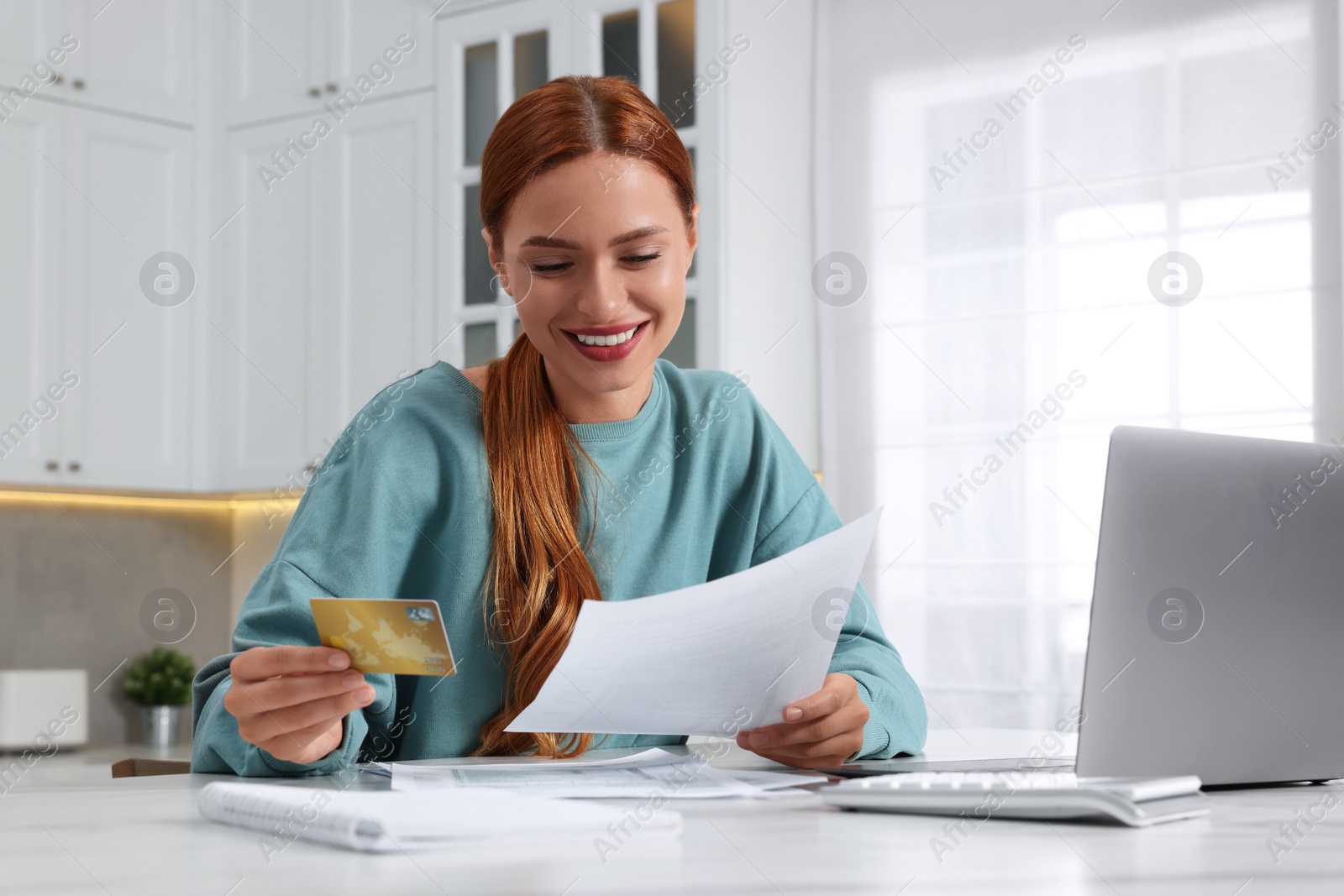 Photo of Woman with credit card using laptop for paying taxes online at home