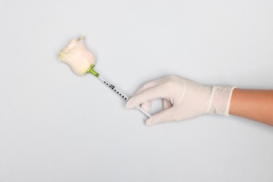 Photo of Doctor making injection to rose on light grey background, top view