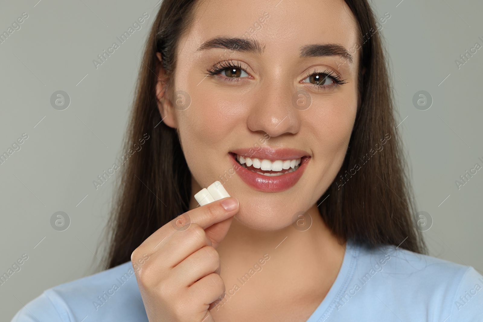 Photo of Happy young woman with bubble gums on grey background