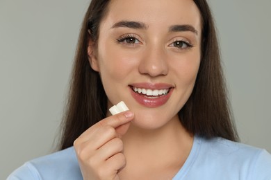 Happy young woman with bubble gums on grey background