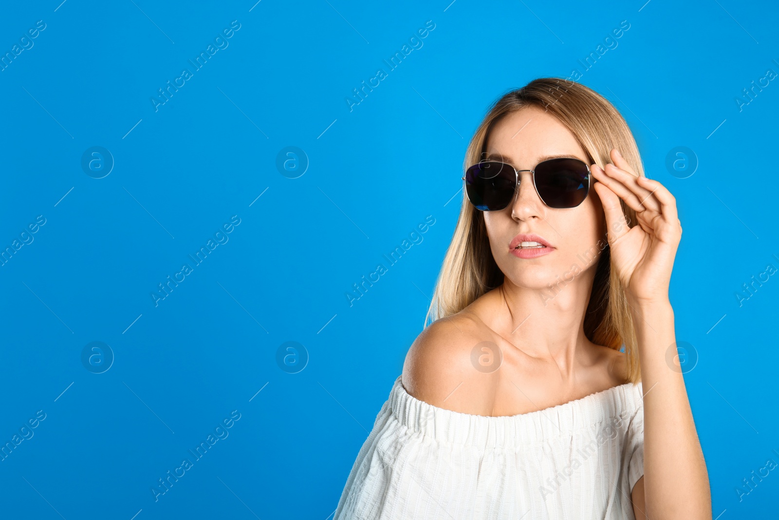 Photo of Beautiful woman in stylish sunglasses on light blue background, space for text
