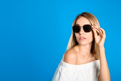 Photo of Beautiful woman in stylish sunglasses on light blue background, space for text