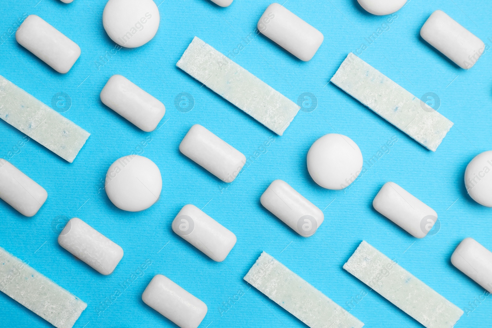 Photo of White bubble gums on blue background, flat lay