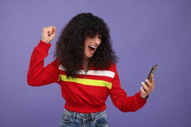 Excited sports fan looking at smartphone and celebrating on violet background