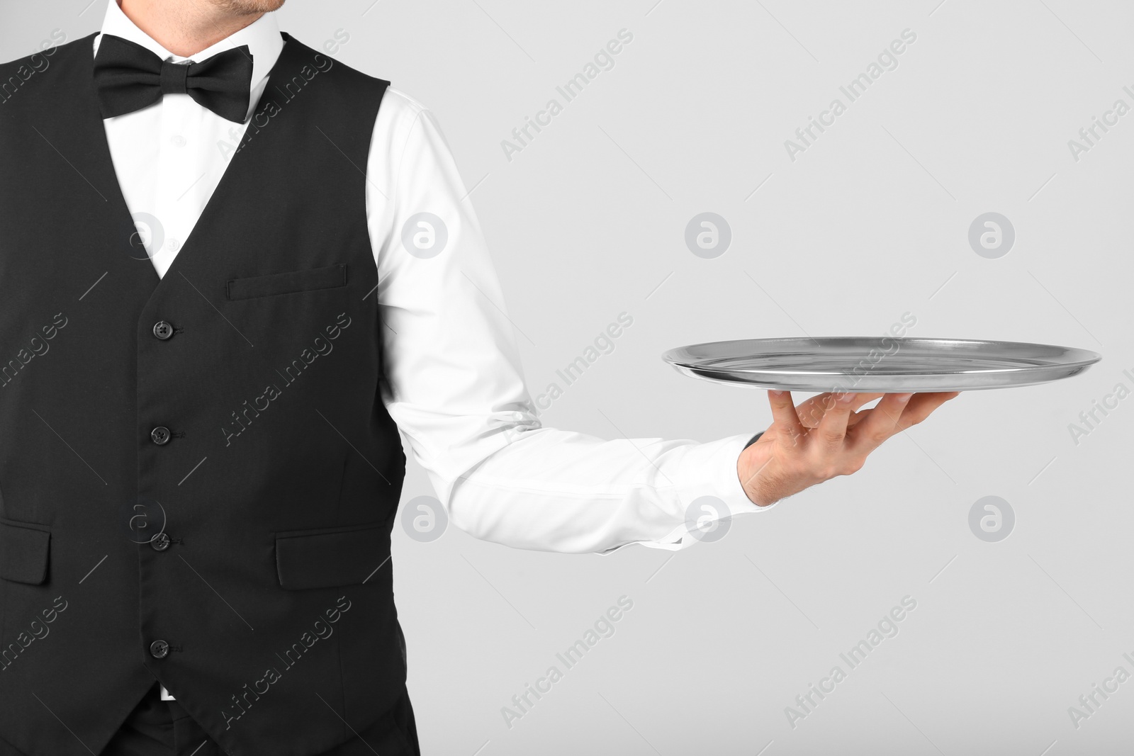 Photo of Waiter holding metal tray on light background